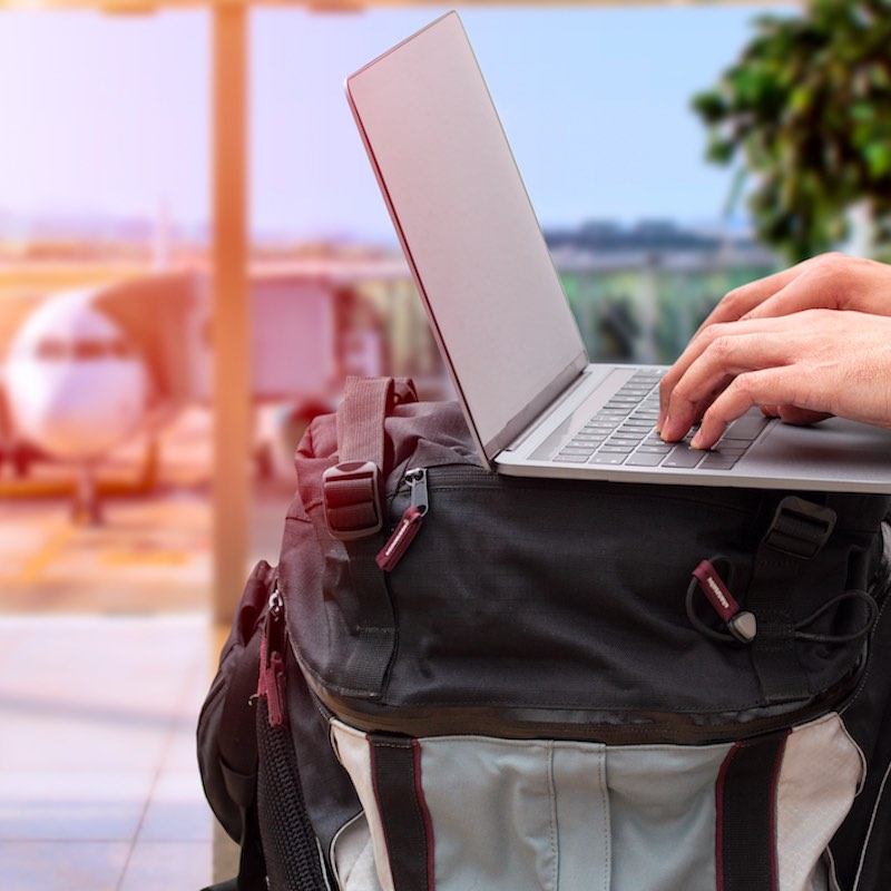Persona que utiliza una computadora portátil para buscar información sobre vacaciones.