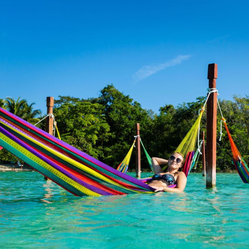 Turista femenina descansando en una hamaca en la laguna de Bacalar en Bacalar, México