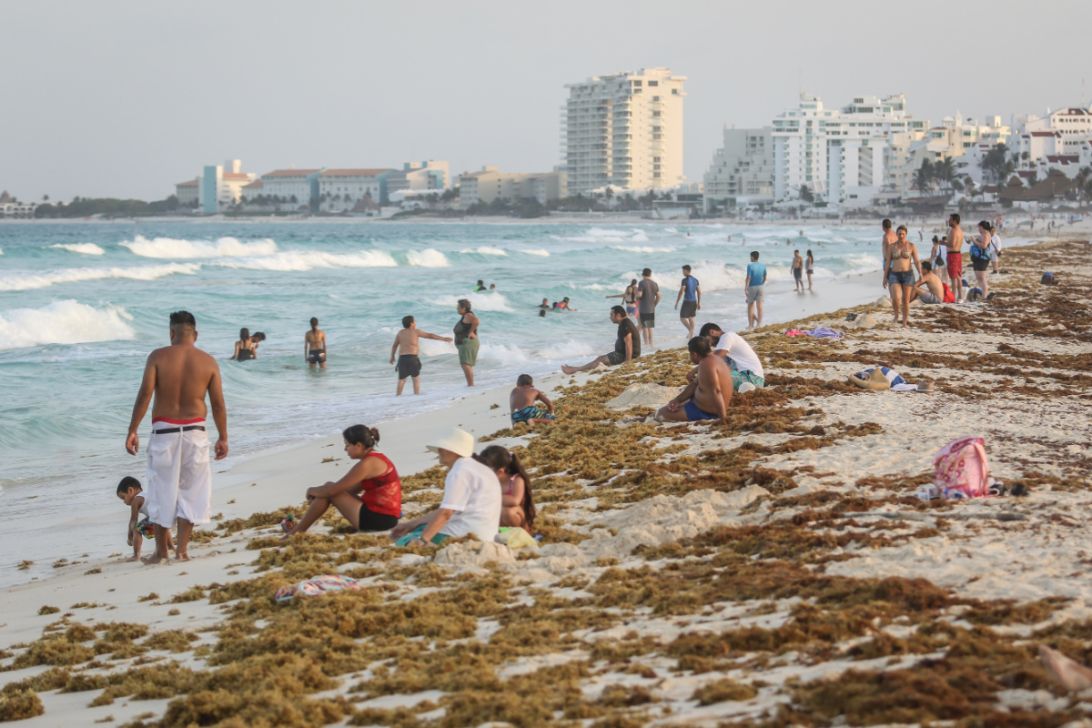 Playa Delfines en Cancún, México cubierta de sargazo y llena de turistas