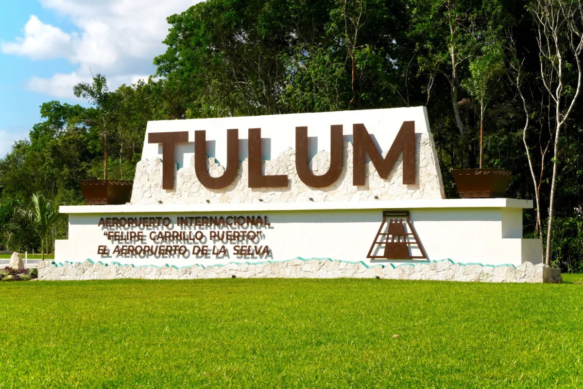 Césped verde y letrero frente al aeropuerto internacional de Tulum