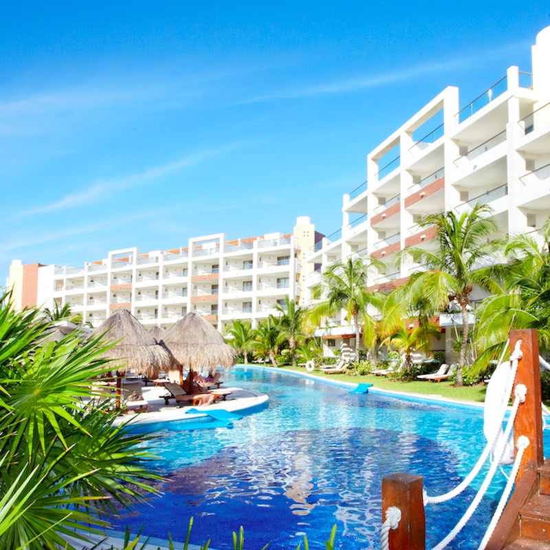 Piscina en un resort caribeño durante el día. Cielos soleados y azules arriba.